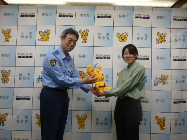 警視庁のマスコットキャラクター「ピーポくん」のぬいぐるみを受取る大和自動車交通のデザイン担当者