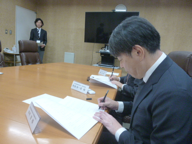大和交通保谷㈱中村社長が調印式で書類記入をしている写真です。