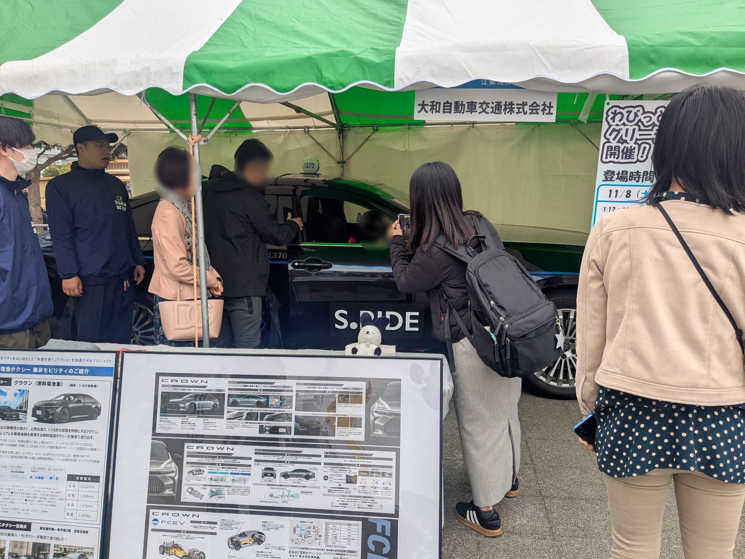 水素タクシーの運転席に乗る子供と写真を撮る保護者