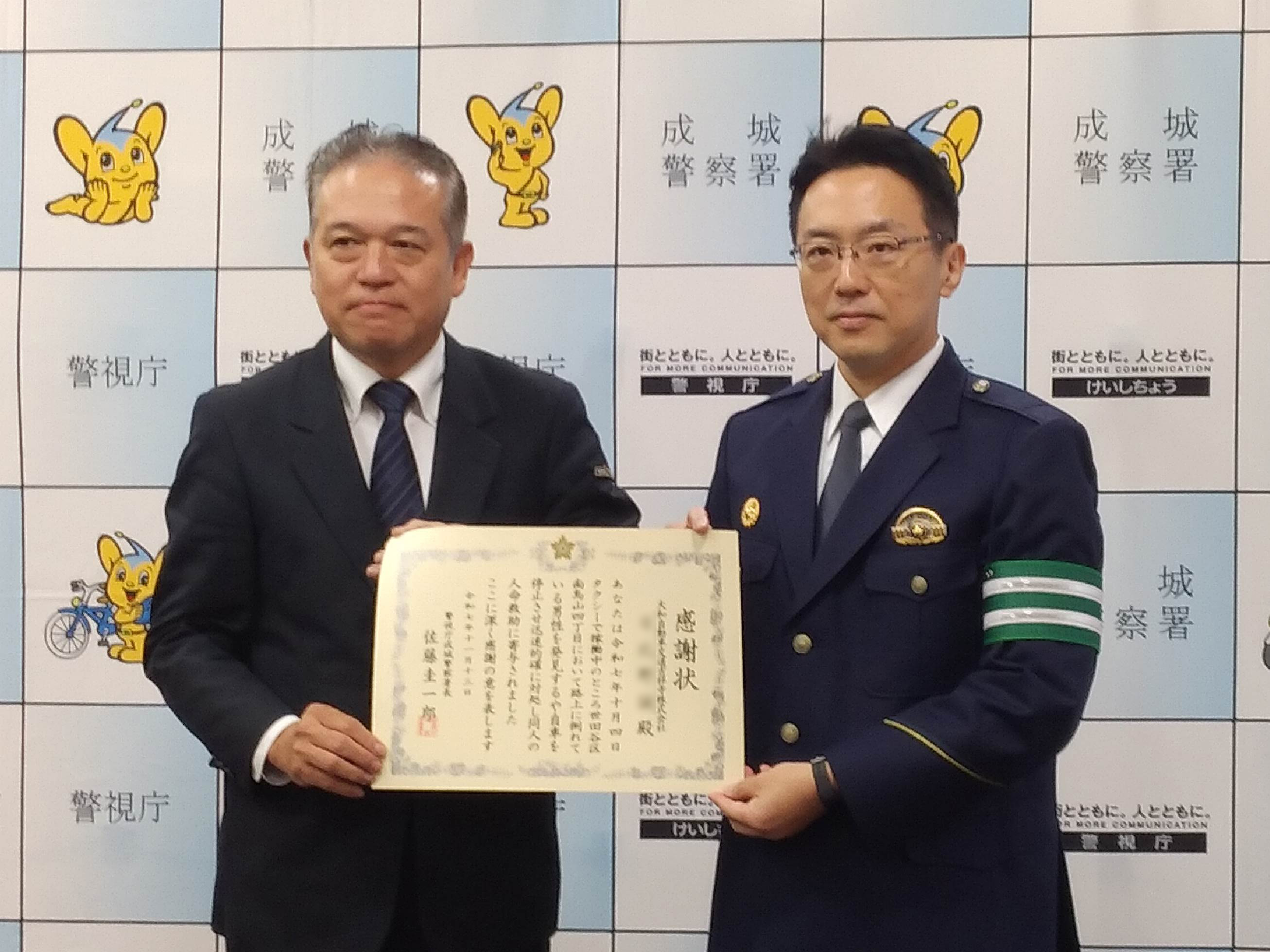 大和自動車交通吉祥寺㈱の乗務員が、成城警察署の方と共に感謝状を持ち正面を向いている写真。