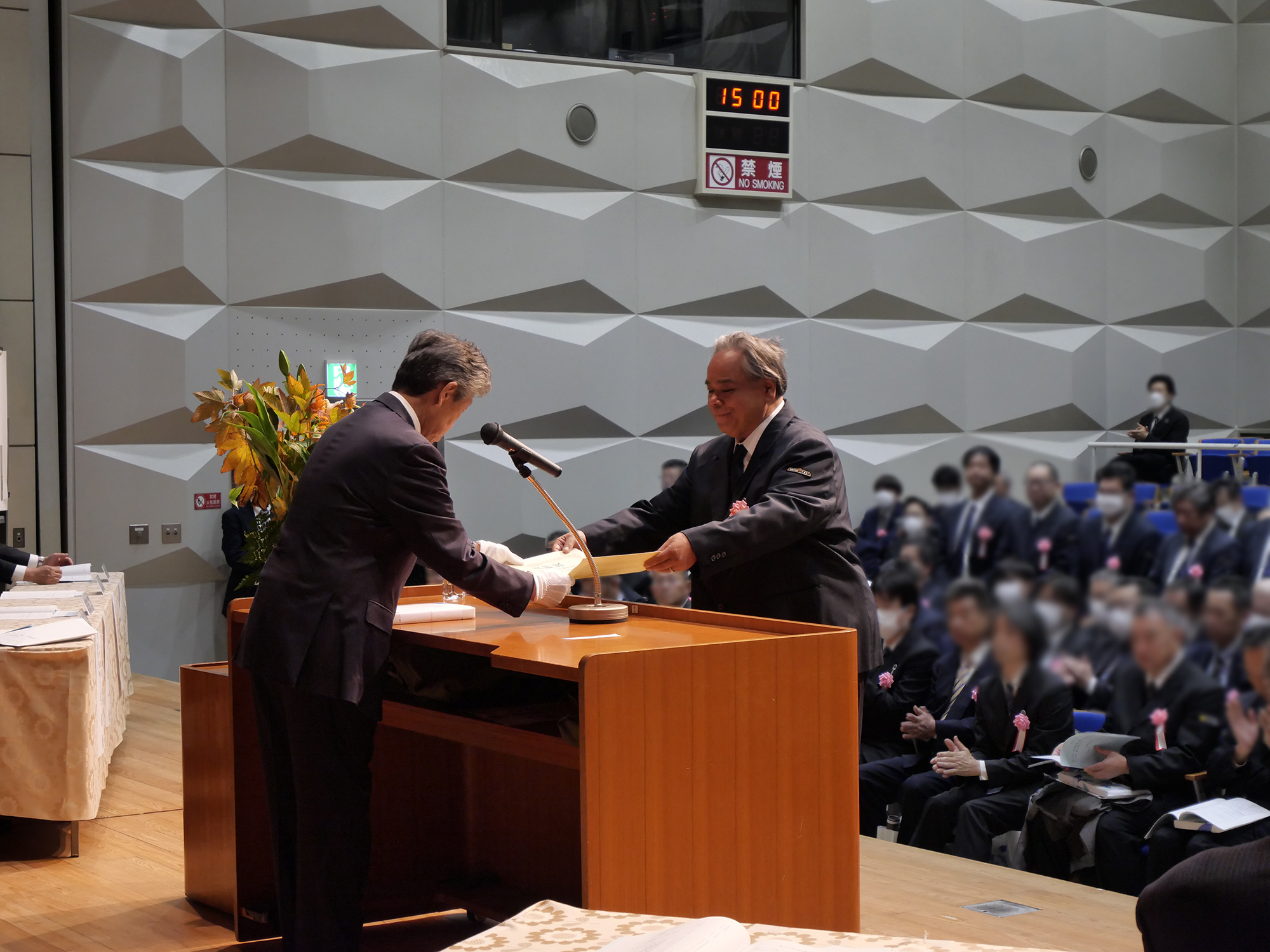 大和自動車交通立川㈱の乗務員が、3年表彰・立川地区の代表として表彰式の舞台上に登壇し、賞状を受け取っている写真