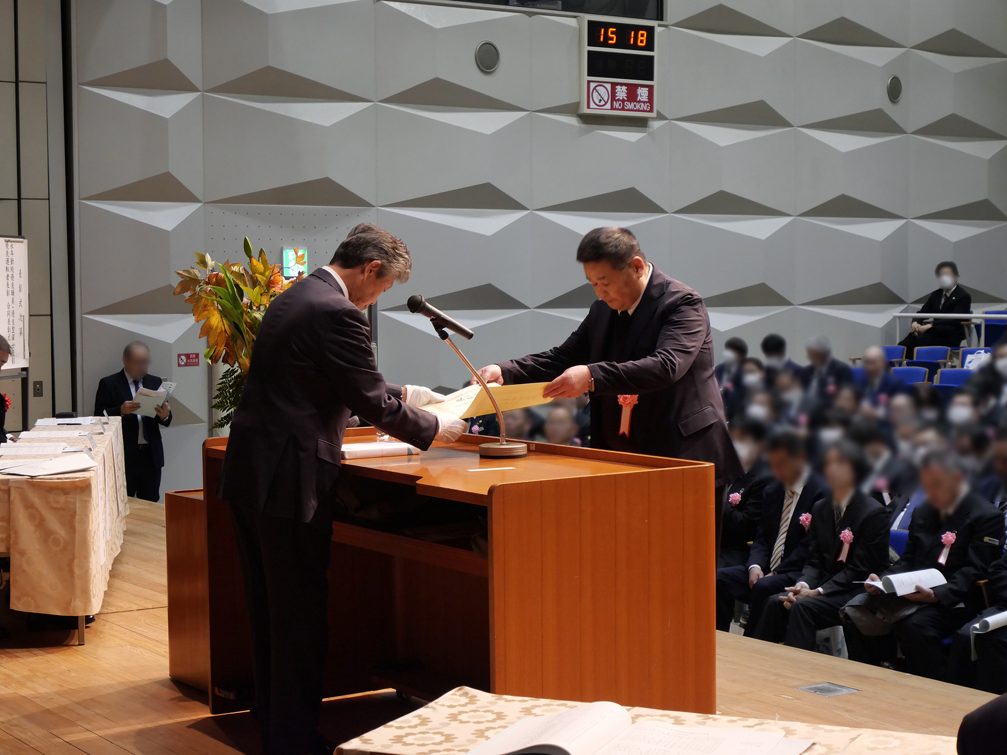 大和交通保谷㈱の乗務員が、15年表彰・北多摩東地区の代表として表彰式の舞台上に登壇し、賞状を受け取っている写真